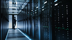 person standing at the end of a data center aisle